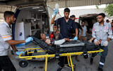 A Palestinian boy, who was injured by gunfire while waiting for aid trucks entering the northern Gaza Strip through Zikim crossing, is taken out of an ambulance after arriving for medical care at the Shifa Hospital in Gaza City, July 27, 2025. (Omar Al-Qattaa/AFP)