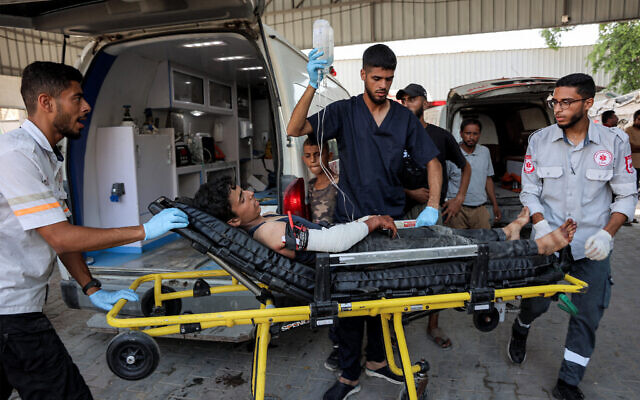 A Palestinian boy, who was injured by gunfire while waiting for aid trucks entering the northern Gaza Strip through Zikim crossing, is taken out of an ambulance after arriving for medical care at the Shifa Hospital in Gaza City, July 27, 2025. (Omar Al-Qattaa/AFP)
