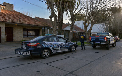 A member of the Argentine Federal Police (PFA) stands outside the house that was raided (L) after a photo showing 17th century masterwork 'Portrait of a Lady' by Italian baroque portraitist Giuseppe Ghislandi, allegedly stolen by the Nazis from a Dutch Jewish art collector, appeared in an advertisement for the sale of the property, in Parque Luro neighborhood, Mar del Plata, Argentina, on August 27, 2025. (Mara Sosti / AFP)