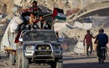 A Palestinian flag flies from a truck carrying people and children with their belongings as people evacuate southbound from Gaza City on September 2, 2025. (Eyad BABA / AFP)