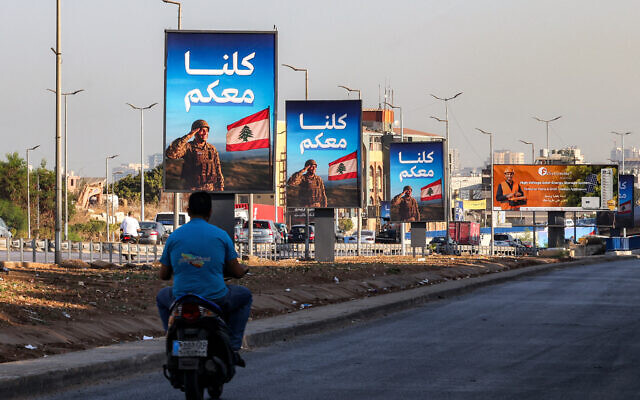 A man rides a scooter past signs depicting a Lebanese soldier saluting the national flag with the Arabic slogan 'We are all with you' along the highway leading to Beirut International Airport in southern Beirut on September 5, 2025. (ANWAR AMRO / AFP) A man rides a scooter past signs depicting a Lebanese soldier saluting the national flag with the Arabic slogan 'We are all with you' along the highway leading to Beirut International Airport in southern Beirut on September 5, 2025. (ANWAR AMRO / AFP)