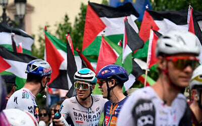 Pro-Palestinian, anti-Israel protesters wave flags as riders await the start of the 15th stage of the Vuelta a Espana cycling tour, a 167 km race between A Veiga/Vegadeo and Monforte de Lemos, on September 7, 2025. (Miguel RIOPA / AFP)