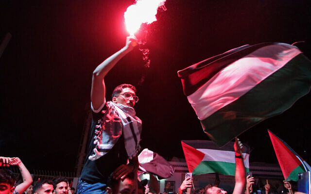 Tunisian protesters shout anti-Israeli slogans and wave Palestinian flags at the Port of Sidi Bou Said near Tunis on September 9, 2025, after the organizers of a Gaza-bound flotilla carrying humanitarian aid and pro-Palestinian activists said late on September 8 that one of their boats was hit by a suspected drone. (YASSINE MAHJOUB / AFP)