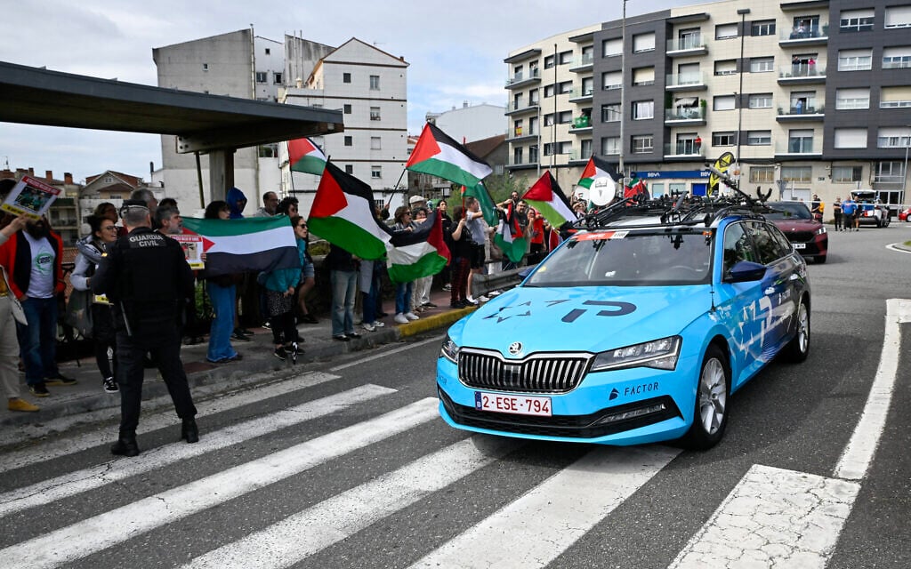Pro-Palestinian protesters wave flags and shout as Team Israel Premier Tech's team car drives by in Poio at the start of the 16th stage of the Vuelta a Espana, a 172 km race between Poio and Castro de Herville, on September 9, 2025. (Miguel RIOPA / AFP)