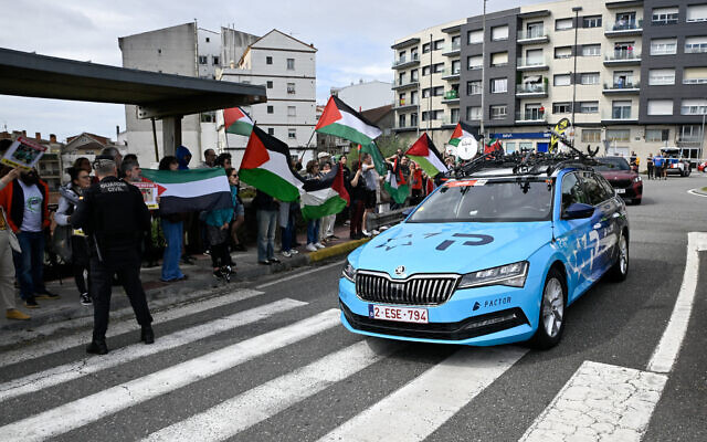 Pro-Palestinian protesters wave flags and shout as Team Israel Premier Tech's team car drives by in Poio at the start of the 16th stage of the Vuelta a Espana, a 172 km race between Poio and Castro de Herville, on September 9, 2025. (Miguel RIOPA / AFP)