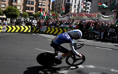 Pro-Palestinian, anti-Israel protesters wave Palestinian flags as Team Israel Premier Tech's Israeli rider Nadav Raisberg competes during the 18th stage of the Vuelta a Espana on September 11, 2025. (Photo by Miguel RIOPA / AFP)
