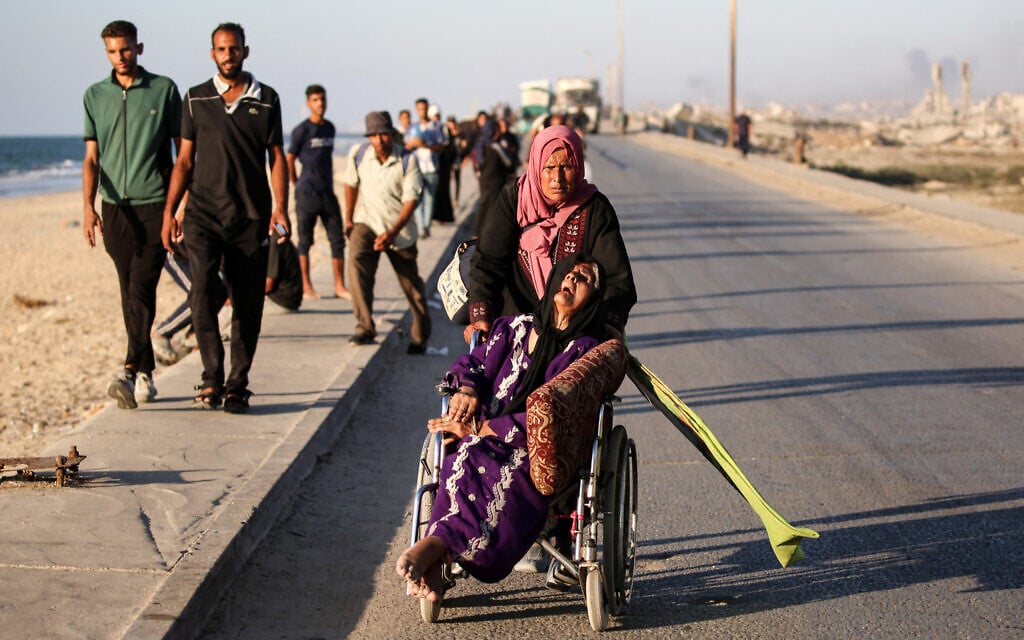 A woman pushes the wheelchair of an elderly person as Palestinians flee south from Gaza City via on the coastal road near the Nuseirat refugee camp in the central Gaza Strip, on September 12, 2025. (Eyad BABA / AFP) A woman pushes the wheelchair of an elderly person as Palestinians flee south from Gaza City via on the coastal road near the Nuseirat refugee camp in the central Gaza Strip, on September 12, 2025. (Eyad BABA / AFP)