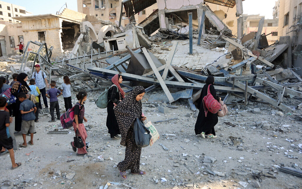 Displaced Palestinians carry their belongings as they walk past the rubble of a building, leveled in an overnight Israeli strike in the Rimal neighborhood of Gaza City on September 13, 2025 (Omar AL-QATTAA / AFP)
