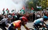 Cyclists ride as Pro-Palestinians protesters hold Palestinian flags during the 20th stage of the Vuelta a Espana 2025, in El Escorial, Spain, September 13, 2025. (Pierre-Philippe Marcou / AFP)
