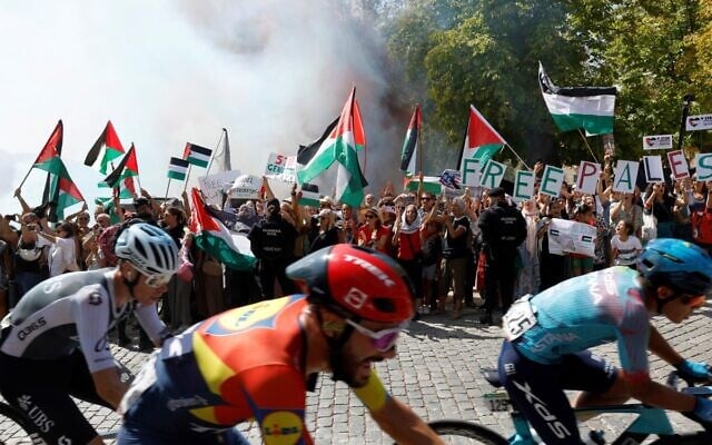 Cyclists ride as Pro-Palestinians protesters hold Palestinian flags during the 20th stage of the Vuelta a Espana 2025, in El Escorial, Spain, September 13, 2025. (Pierre-Philippe Marcou / AFP) Cyclists ride as Pro-Palestinians protesters hold Palestinian flags during the 20th stage of the Vuelta a Espana 2025, in El Escorial, Spain, September 13, 2025. (Pierre-Philippe Marcou / AFP)