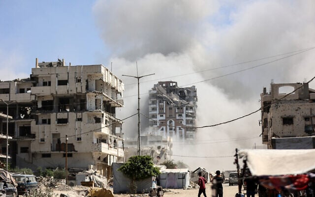 Palestinians watch as the Mhanna tower collapses amid heavy smoke, during an Israeli strike in the Tal el-Hawa neighbourhood of Gaza City on September 14, 2025. (Omar AL-QATTAA / AFP)