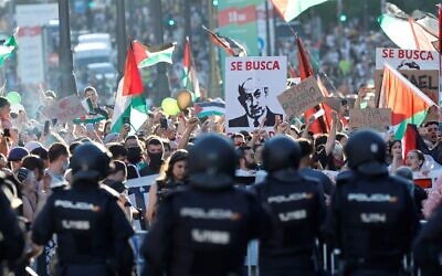 Pro-Palestinian, anti-Israel protestors hold a 'Wanted' poster depicting Prime Minister Benjamin Netanyahu, during the 21st and last stage of the Vuelta a Espana 2025, in Madrid on September 14, 2025. (Oscar DEL POZO / AFP)