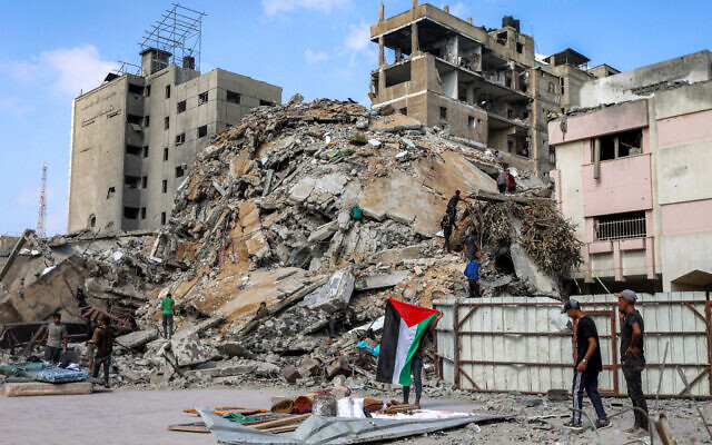A boy unfurls a Palestinian flag as people inspect the rubble of the Unknown Soldier Tower, after it was destroyed by overnight Israeli strikes, in the Rimal neighborhood of Gaza City, September 15, 2025. (Omar AL-QATTAA / AFP)