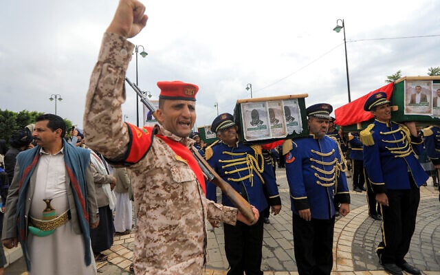 A fighter loyal to Yemen's Houthis reacts and gestures as members of an honor guard carry caskets during a funeral for Houthi members who were killed the previous week in an Israeli airstrike, outside the Saleh Grand Mosque in the Houthi-held capital Sanaa on September 16, 2025.  (Photo by Mohammed HUWAIS / AFP)