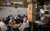 Palestinian men play cards together at a coffee shop in the West Bank city of Ramallah on September 22, 2025. (John Wessels/AFP)
