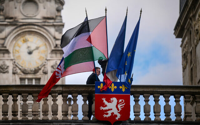 An employee places the Palestinian flag along side the French Flag, the flag of Lyon, and the European Union flag, over the entrance of the Lyon City Hall, in eastern France, on the day France plans the recognition of a Palestinian State at the United Nations on September 22. (Photo by OLIVIER CHASSIGNOLE / AFP)
