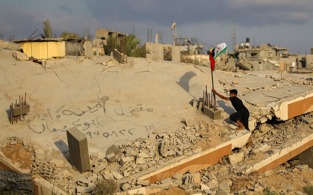 A Palestinian child raises a Palestinian flag as he climbs on the rubble of a destroyed building at the Bureij camp in the central Gaza Strip on September 22, 2025.(Photo by Eyad BABA / AFP)