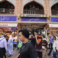 Illustrative: Iranians walk past shops at the Grand Bazaar in Tehran on September 27, 2025. (ATTA KENARE / AFP)
