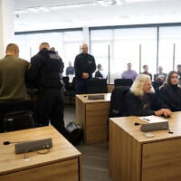 Defendants Jian G (L) is being uncuffed as co-defendant and Yaqi X (R) sits at her place in the courtroom of the higher regional court in Dresden, eastern Germany, on September 30, 2025. (Odd ANDERSEN / POOL / AFP)