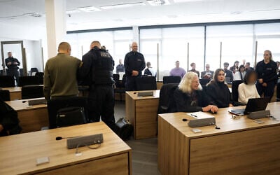 Defendants Jian G (L) is being uncuffed as co-defendant and Yaqi X (R) sits at her place in the courtroom of the higher regional court in Dresden, eastern Germany, on September 30, 2025. (Odd ANDERSEN / POOL / AFP)