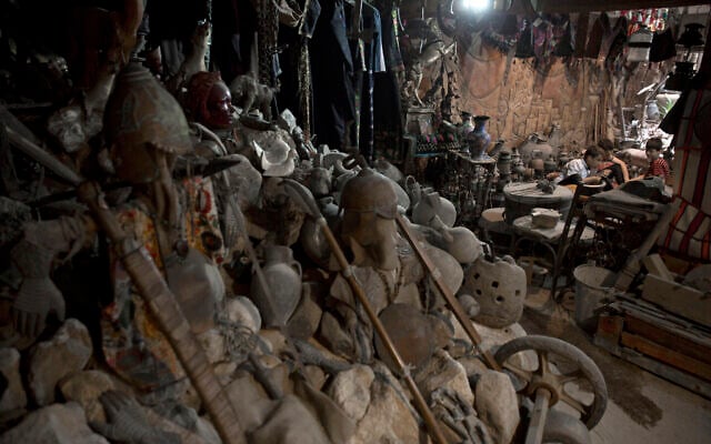 In this July 17, 2019 photo, young Palestinians sit among ancient artifacts displayed inside Shahwan private museum in a basement of a building in town of Khan Younis, Southern Gaza Strip. (AP Photo/Khalil Hamra)