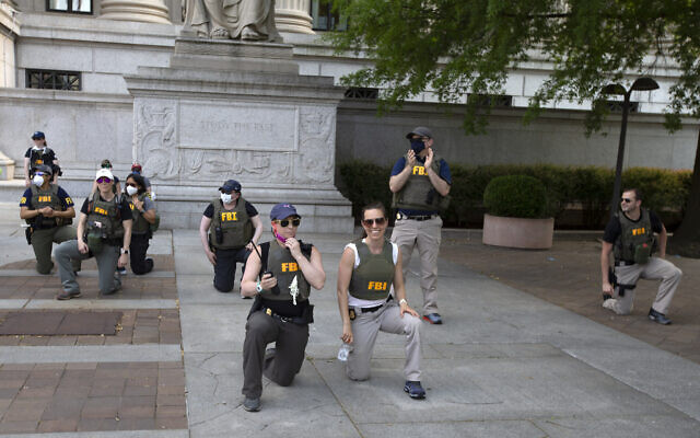 Federal Bureau of Investigation (FBI) officers take a knee with demonstrators, as they march on Pennsylvania Avenue, June 4, 2020, in Washington, during a protest over the death of George Floyd, an unarmed black man, who died after a police officer kneeled on his neck for several minutes. (AP Photo/Jose Luis Magana) Federal Bureau of Investigation (FBI) officers take a knee with demonstrators, as they march on Pennsylvania Avenue, June 4, 2020, in Washington, during a protest over the death of George Floyd, an unarmed black man, who died after a police officer kneeled on his neck for several minutes. (AP Photo/Jose Luis Magana)