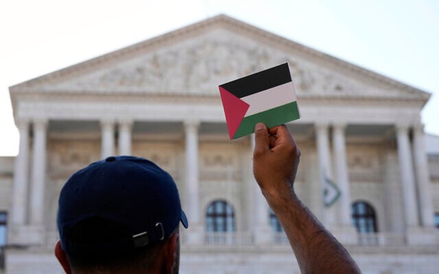 A man holds up a Palestinian flag postcard during a protest calling for the recognition of a Palestinian state outside the Portuguese parliament in Lisbon, June 17, 2025. (AP Photo/Armando Franca)
