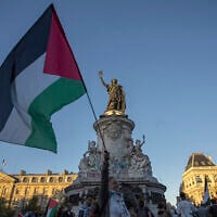 A woman holds a Palestinian flag at Republic Square in Paris, Sep. 17, 2025. (AP Photo/Aurelien Morissard)