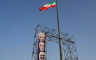 A worker hangs a banner showing portraits of the late Iranian armed forces commanders, Gen. Mohammad Hossein Bagheri, top, Gen. Gholamali Rashid, center, and Gen. Hossein Salami who were killed in Israeli strikes in June at Baharestan Square in Tehran, Monday, Sept. 22, 2025. (AP Photo/Vahid Salemi)