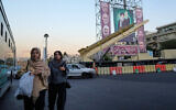 People walk past a domestically-built 'Khaibar-buster' missile and banners showing portraits of the Iranian Supreme Leader Ayatollah Ali Khamenei, center, and armed forces commanders who were killed in Israeli strikes in June, displayed in a military exhibition commemorating the anniversary of the start of the 1980-88 Iraq-Iran war, and 12-day war with Israel in June, at Baharestan Square in Tehran, September 25, 2025. (AP Photo/Vahid Salemi)
