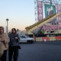 People walk past a domestically-built 'Khaibar-buster' missile and banners showing portraits of the Iranian Supreme Leader Ayatollah Ali Khamenei, center, and armed forces commanders who were killed in Israeli strikes in June, displayed in a military exhibition commemorating the anniversary of the start of the 1980-88 Iraq-Iran war, and 12-day war with Israel in June, at Baharestan Square in Tehran, September 25, 2025. (AP Photo/Vahid Salemi)