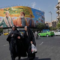 Two women walk past a huge banner showing the late commander of the Iran's Revolutionary Guard expeditionary Quds Force, Gen. Qassem Soleimani, who was killed in a US drone attack in 2020, and two late Hezbollah leaders Hassan Nasrallah, center, and Hashem Safieddine, who were killed in Israeli airstrikes in 2024, at the Enqelab-e-Eslami (Islamic Revolution) square, in Tehran, Iran, September 27, 2025. (AP Photo/Vahid Salemi)