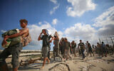 Palestinians carry food parcels and supplies from a GHF aid distribution point in central Gaza, August 5, 2025. (Ali Hassan/Flash90)