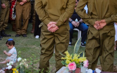 Family and friends of Israeli soldier Sergeant First Class (Res.) Ariel Lubliner attend his funeral as his infant son crawls atop his grave at the Tzur Shalom Cemetery in Kiryat Bialik on September 1, 2025. (Itay Cohen/Flash90)
