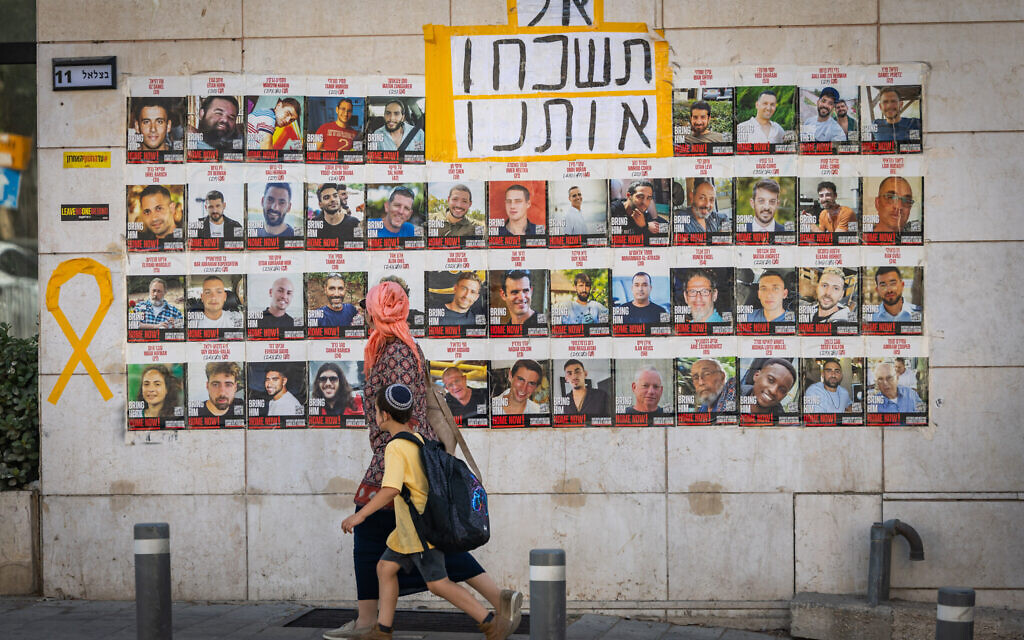 People walk past photos of the Gaza hostages, in Jerusalem, September 2, 2025. (Chaim Goldberg/Flash90)