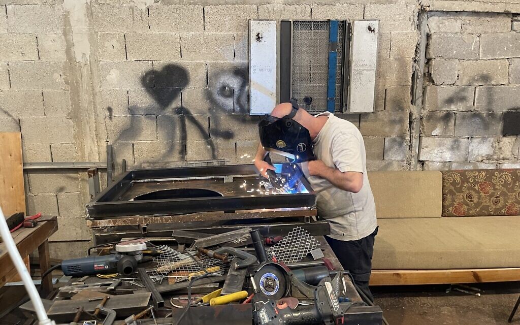 Artist Avinadav Begin at work in his Even Sapir workshop on September 21, 2025 (Jessica Steinberg/Times of Israel)