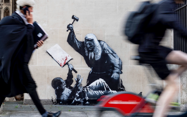 An undated photo released by Banksy of the new artwork by the artist which portrays a judge beating a protester with a gavel at the Royal Courts of Justice in London. (Banksy via AP) An undated photo released by Banksy of the new artwork by the artist which portrays a judge beating a protester with a gavel at the Royal Courts of Justice in London. (Banksy via AP)