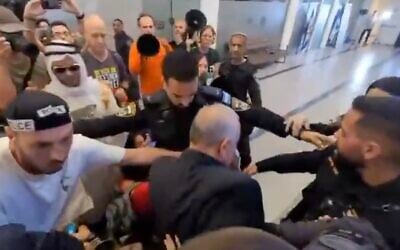 Police officers surround Likud MK Eli Dallal after he fell to the ground while walking through a crowd of anti-government protesters outside a Likud event in Kfar Saba, central Israel, on September 20, 2025. (Screenshot, X; used in accordance with Clause 27a of the Copyright Law)