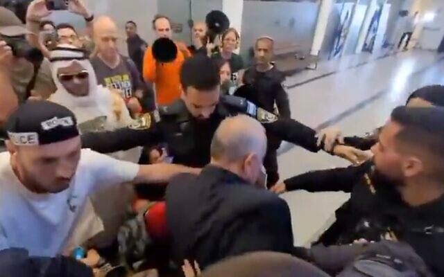 Police officers surround Likud MK Eli Dallal after he fell to the ground while walking through a crowd of anti-government protesters outside a Likud event in Kfar Saba, central Israel, on September 20, 2025. (Screenshot, X; used in accordance with Clause 27a of the Copyright Law)