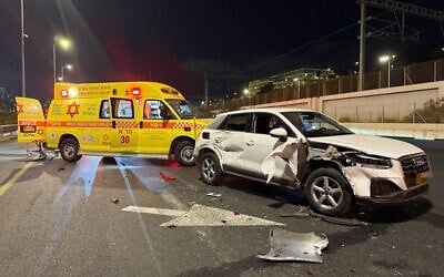 A vehicle is seen damaged, next to an ambulance, after a car accident in which Israeli singer Gidi Gov was involved, on the Ayalon Highway, September 15, 2025. (Magen David Adom)