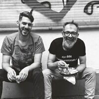 Jalil Dabit, right, wears a shirt that translates to 'I am a hummussexual.' He and Oz Ben David opened Kanaan in 2015. (Elisabeth Patrikiou via JTA)