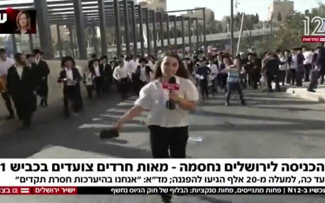 Young ultra-Orthodox men throw plastic bottles at Channel 12 reporter Inbar Twizer, as she tries to broadcast from the scene of a mass rally in Jerusalem against efforts to conscript Haredi men to the military. (Channel 12 screenshot)
