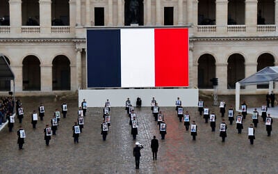 French President Emmanuel Macron (center) stands in front of members of the French Republican Guard holding portraits of French citizens killed in the October 7, 2023, Hamas atrocities, during a ceremony at the Invalides memorial complex in Paris, on February 7, 2024. (Photo by Ludovic MARIN / AFP)
