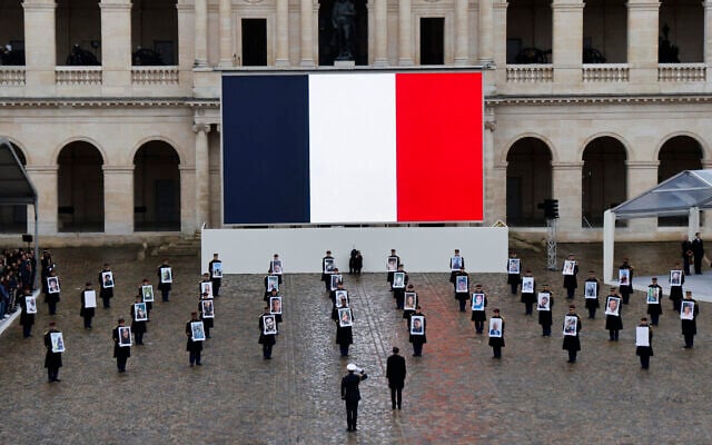 French President Emmanuel Macron (center) stands in front of members of the French Republican Guard holding portraits of French citizens killed in the October 7, 2023, Hamas atrocities, during a ceremony at the Invalides memorial complex in Paris, on February 7, 2024. (Photo by Ludovic MARIN / AFP) French President Emmanuel Macron (center) stands in front of members of the French Republican Guard holding portraits of French citizens killed in the October 7, 2023, Hamas atrocities, during a ceremony at the Invalides memorial complex in Paris, on February 7, 2024. (Photo by Ludovic MARIN / AFP)