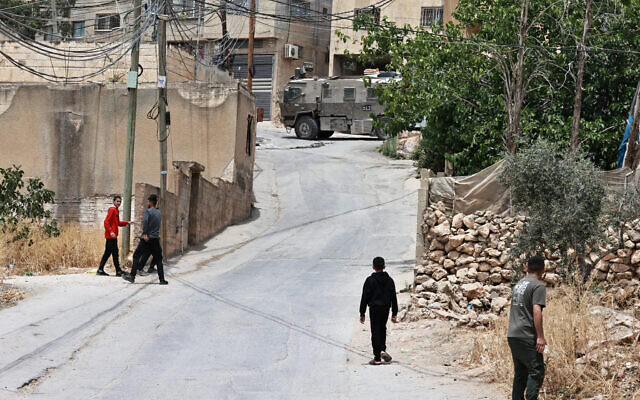 Illustrative: Palestinians hurl rocks towards Israeli army vehicles in the West Bank town of Tamun, near Tubas, on May 15, 2025. (Zain JAAFAR / AFP)