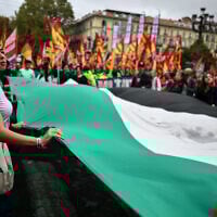 Pro-Palestinians protesters hold a giant Palestinian flag during a protest part of the nationwide strike organized by the Unione Sindacale di Base (USB Union) in Turin, northwestern Italy on September 22, 2025.  (Photo by MARCO BERTORELLO / AFP)