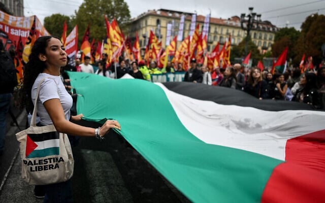Pro-Palestinians protesters hold a giant Palestinian flag during a protest part of the nationwide strike organized by the Unione Sindacale di Base (USB Union) in Turin, northwestern Italy on September 22, 2025.  (Photo by MARCO BERTORELLO / AFP)