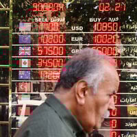 A man walks past an electronic board displaying currency exchange rates in Ferdowsi Square in the Iranian capital Tehran on September 28, 2025. (ATTA KENARE / AFP)