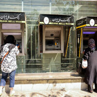People withdraw money from an ATM in the Iranian capital Tehran on September 28, 2025. (Atta Kenare/AFP)