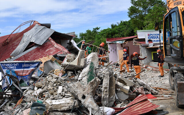 Rescuers search for three people who were reported missing under the rubble of a collapsed building in Bogo City on October 1, 2025, after a powerful 6.9 magnitude earthquake jolted the central Philippines. (TED ALJIBE / AFP)